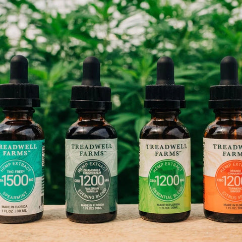Four Treadwell Farms CBD Extracts on a table in front of hemp plants