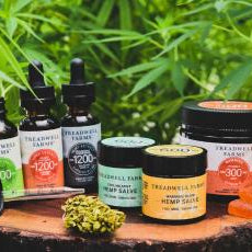 treadwell farms cbd products including 3 extracts, 2 salves, and one jar of gummies with gummies siting in front with hemp plants in the background